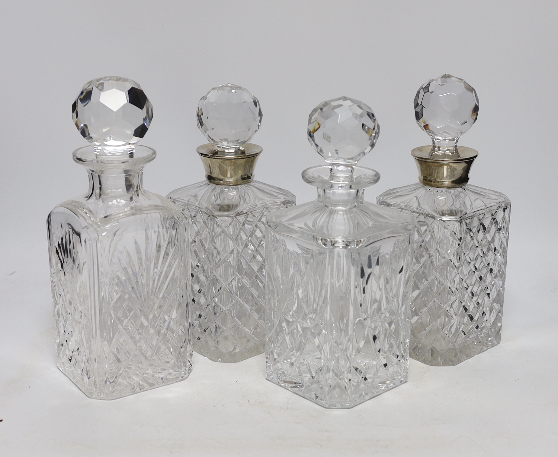 Four crystal glass decanters including a pair with silver mounts, Birmingham 1976, largest 26cm high